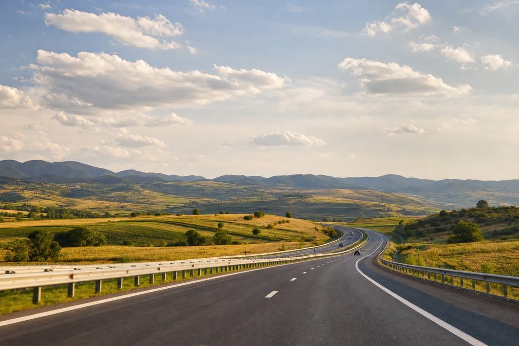 Autostrada in Romania che si snoda attraverso un paesaggio collinare con campi e montagne