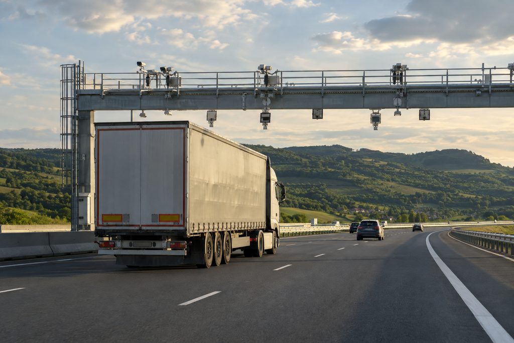 Camion che percorre un'autostrada rumena passando sotto un portale di pedaggio con telecamere