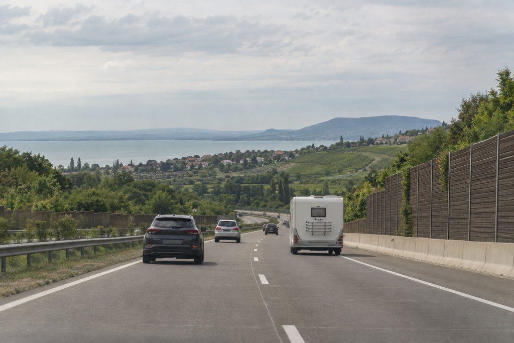 Autoroute en Hongrie avec des voitures et un camping-car dans la circulation et vue sur des vignobles et un lac