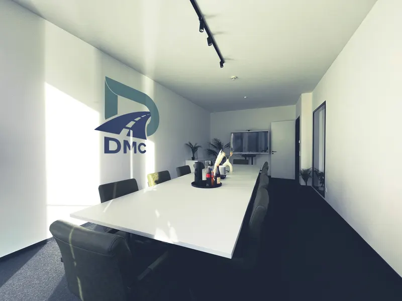 Besprechungsraum mit langem Konferenztisch und DMC-Logo an der Wand